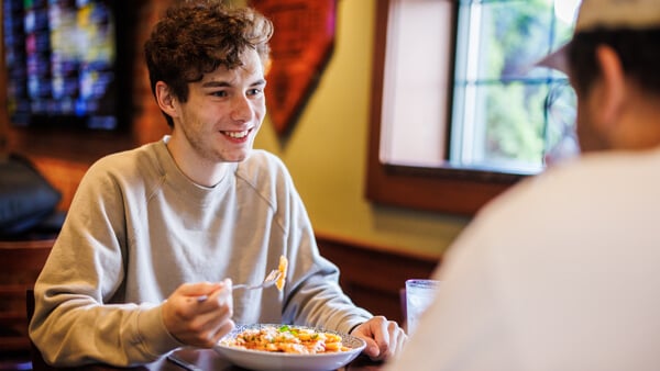 A Quinnipiac student eats a pasta dish in a local restaurant with his family
