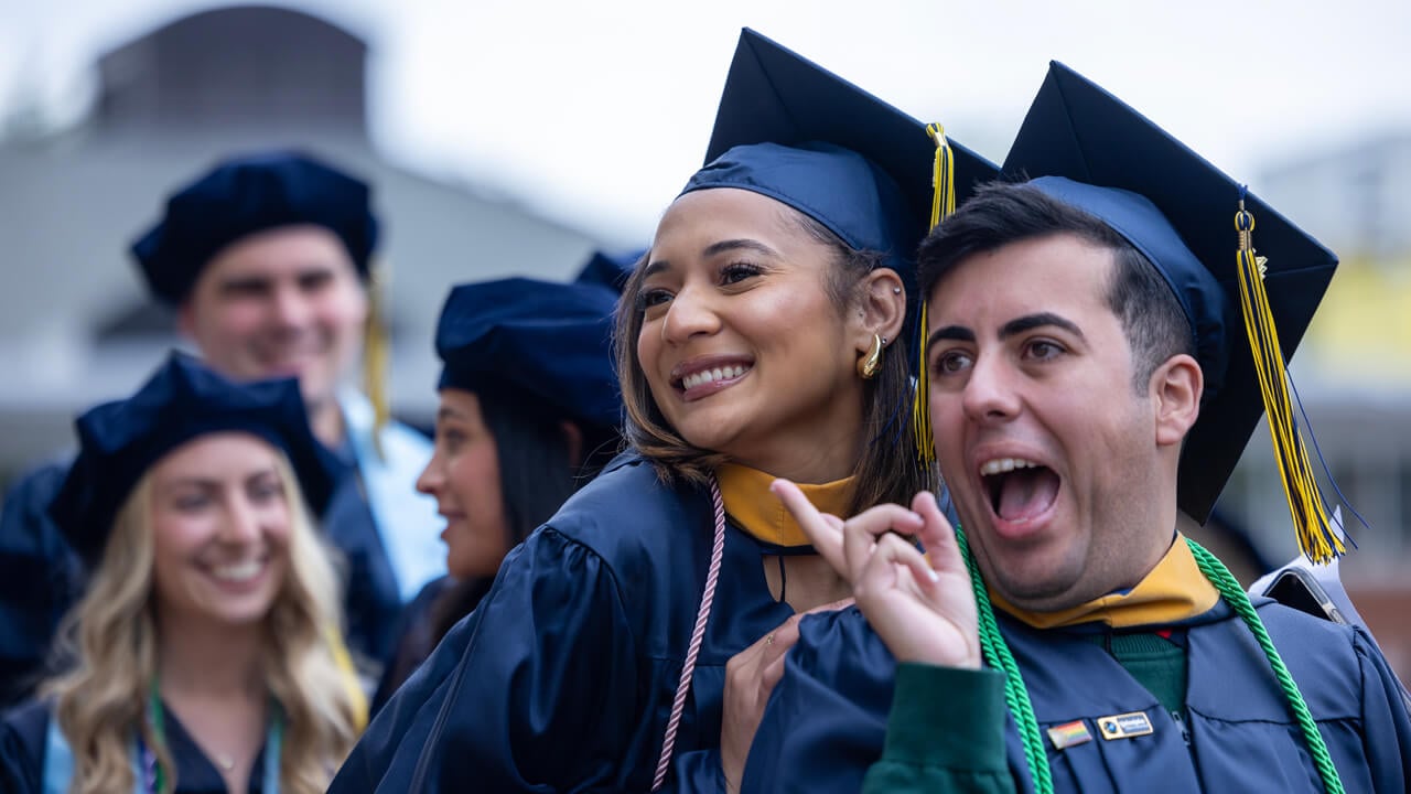 Two health sciences graduates smile broadly and pose for a photo on Commencement day