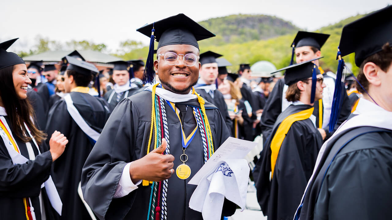 Graduate smiles while holding the Commencement program