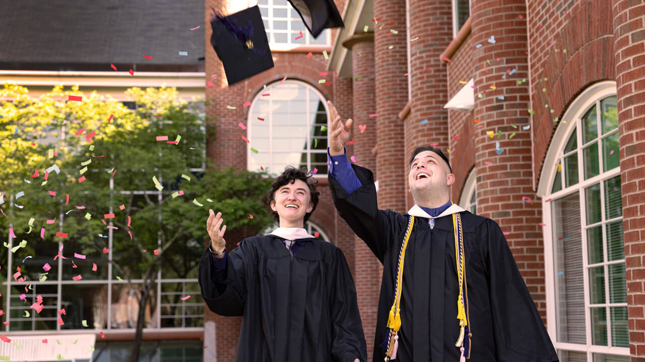 Graduate happily throwing caps in the air along with confetti falling to the ground