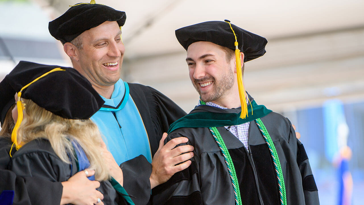Faculty member congratulates graduate student on stage