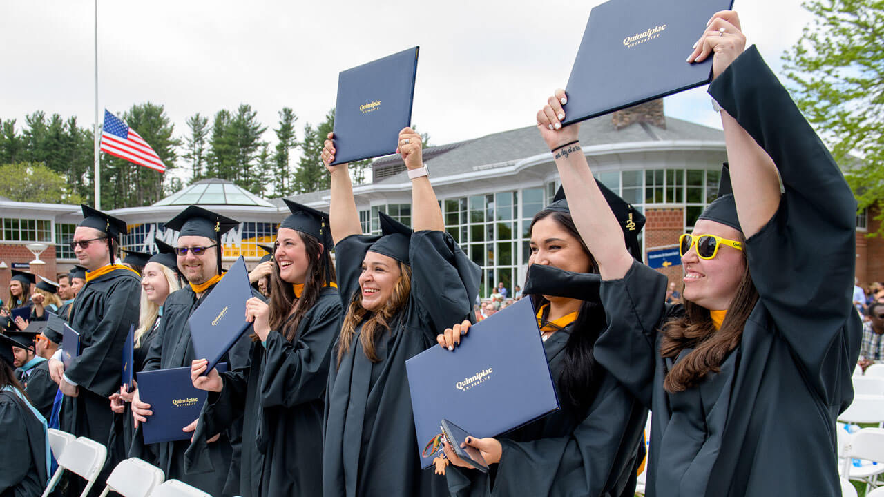 Graduate students hold up their diplomas