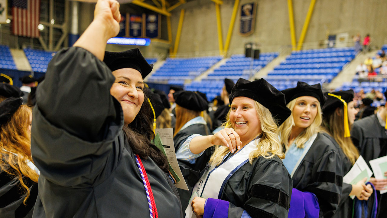 A graduate raises her fist in celebration to the crowd